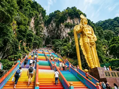 Rainbow-painted steps at Batu Caves Kuala Lumpur with golden Murugan statue